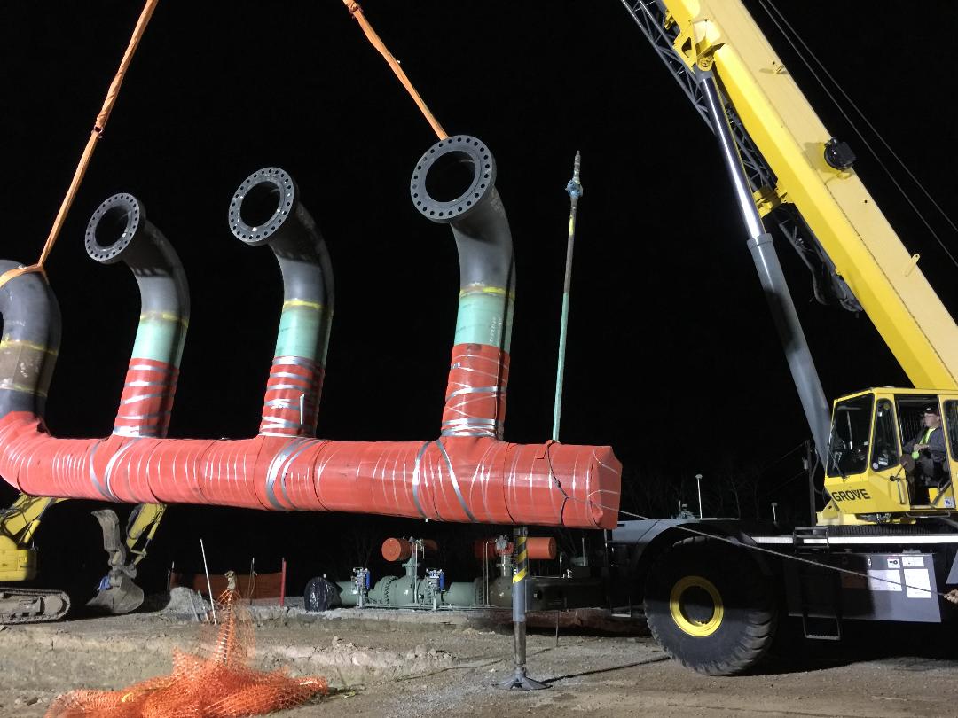 Large fabricated piping assembly being positioned by crane